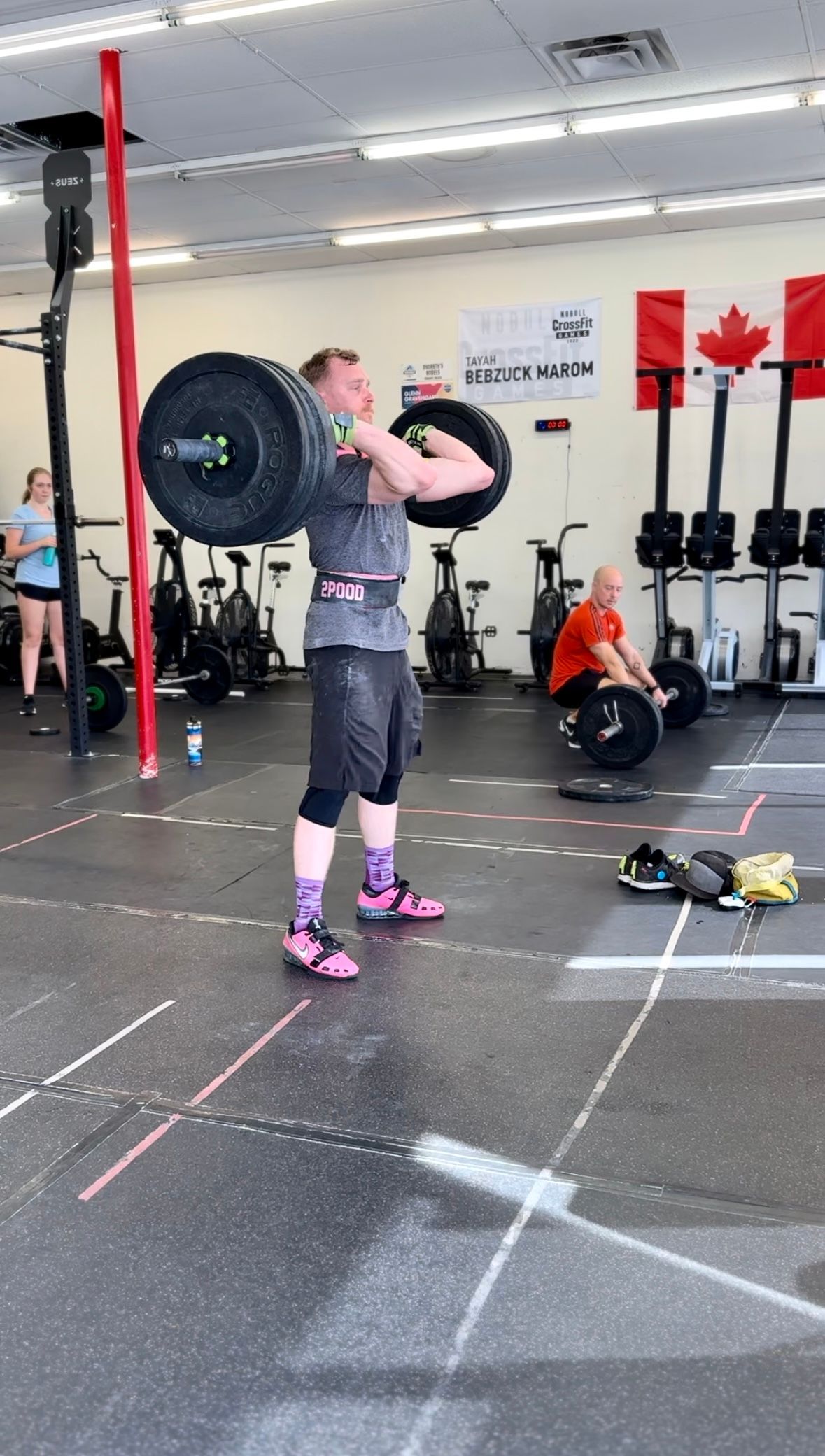 A man is lifting a barbell over his head in a gym.
